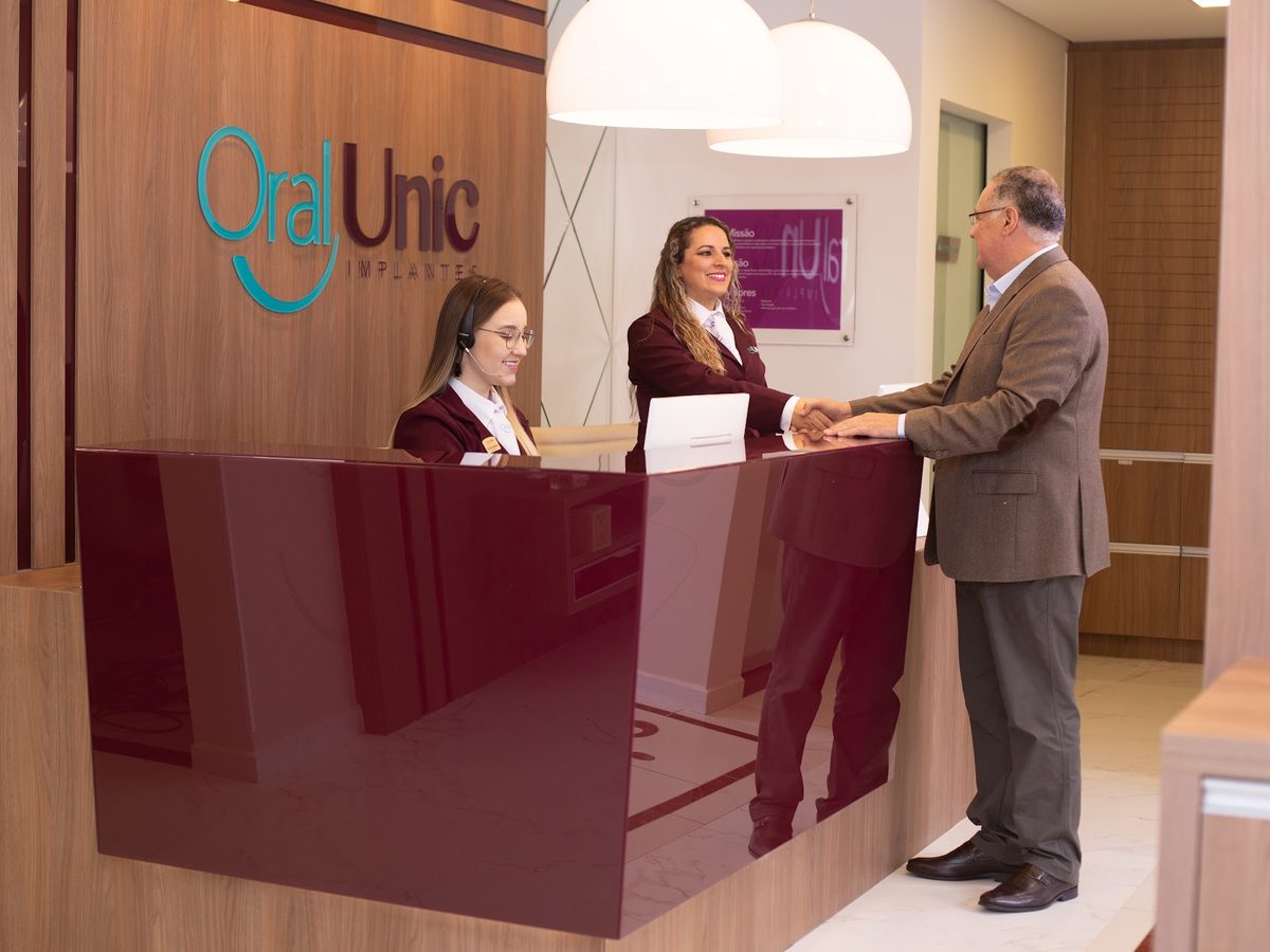 Recepção da Oral Unic Bento Gonçalves com a equipe atendendo um paciente